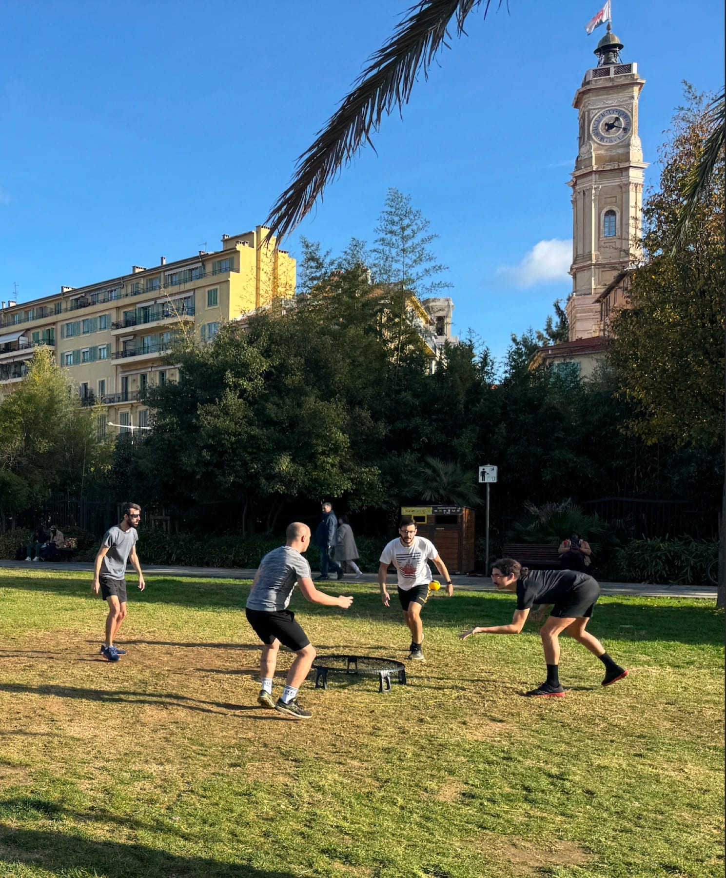 Session de roundnet au Jardin Albert 1er à Nice, quatre joueurs autour du filet avec la tour de l'horloge en arrière-plan